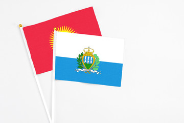 San Marino and Kyrgyzstan stick flags on white background. High quality fabric, miniature national flag. Peaceful global concept.White floor for copy space.