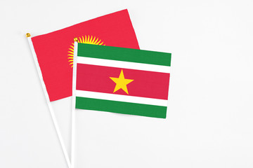 Suriname and Kyrgyzstan stick flags on white background. High quality fabric, miniature national flag. Peaceful global concept.White floor for copy space.