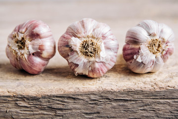 Garlic lie in a row on a rustic wooden background. Copy, empty space for text