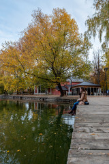 Fototapeta premium Girl with a coat sitting watching the lake of Puigcerda, Catalonia