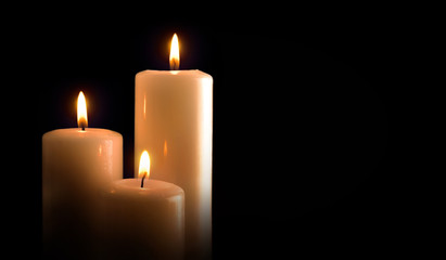 Three burning candles isolated black front view