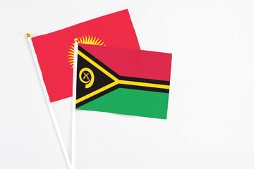 Vanuatu and Kyrgyzstan stick flags on white background. High quality fabric, miniature national flag. Peaceful global concept.White floor for copy space.