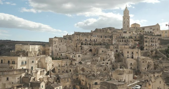 Panorama of the Sassi of Matera with houses in tuff stone. Church with bell tower and stone arch at dawn with sky and clouds.