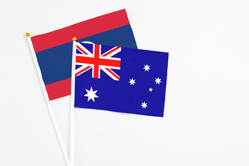 Fototapeta premium Australia and Laos stick flags on white background. High quality fabric, miniature national flag. Peaceful global concept.White floor for copy space.