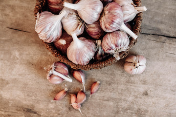 Garlic in a wicker basket on a wooden table background. Top view. Copy, empty space for text