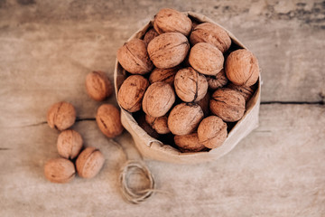 Walnuts in a paper bag on a old rustic table. Walnuts in a paper bag. Top view. Copy, empty space for text