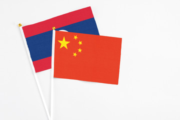 China and Laos stick flags on white background. High quality fabric, miniature national flag. Peaceful global concept.White floor for copy space.