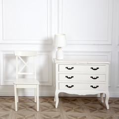 White chest of drawers with a floor lamp and a chair in a light interior