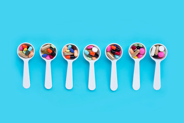 Colorful medicine pills, tablets and capsules on blue background