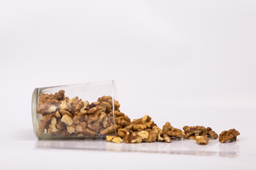 Walnuts in a glass. Scattered peeled nuts. Glass jar with peeled walnuts.