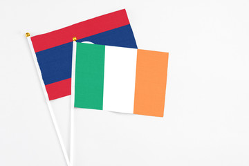 Ireland and Laos stick flags on white background. High quality fabric, miniature national flag. Peaceful global concept.White floor for copy space.