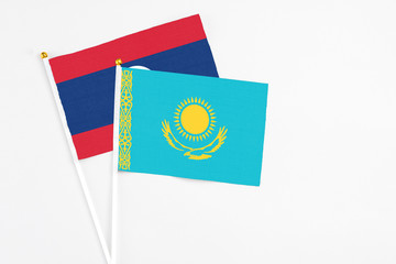 Kazakhstan and Laos stick flags on white background. High quality fabric, miniature national flag. Peaceful global concept.White floor for copy space.