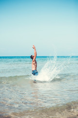 young muscular man posing and splashing around in the sea