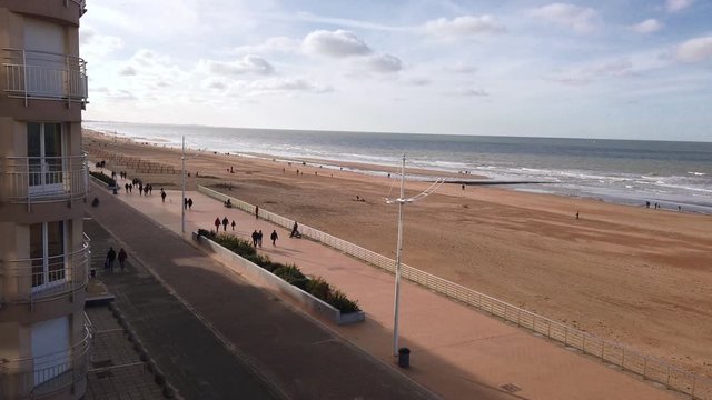 Panning view from a high standpoint on a seawall and beach on belgian coast in autumnal sunlight