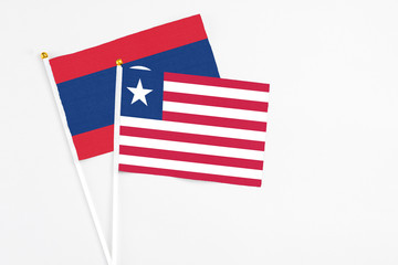 Liberia and Laos stick flags on white background. High quality fabric, miniature national flag. Peaceful global concept.White floor for copy space.