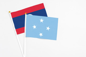 Micronesia and Laos stick flags on white background. High quality fabric, miniature national flag. Peaceful global concept.White floor for copy space.