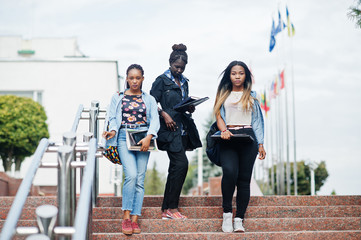 Obraz premium Three african students female posed with backpacks and school items on yard of university.