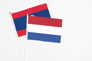 Netherlands and Laos stick flags on white background. High quality fabric, miniature national flag. Peaceful global concept.White floor for copy space.