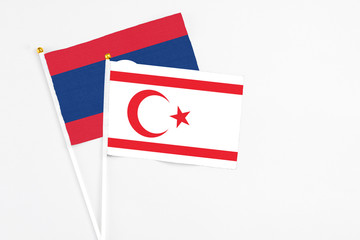 Northern Cyprus and Laos stick flags on white background. High quality fabric, miniature national flag. Peaceful global concept.White floor for copy space.