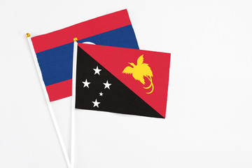 Papua New Guinea and Laos stick flags on white background. High quality fabric, miniature national flag. Peaceful global concept.White floor for copy space.