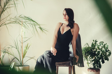 Fototapeta na wymiar Beautiful girl model dressed in black clothes standing near armchair in loft style interior