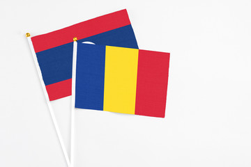 Romania and Laos stick flags on white background. High quality fabric, miniature national flag. Peaceful global concept.White floor for copy space.