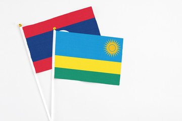 Rwanda and Laos stick flags on white background. High quality fabric, miniature national flag. Peaceful global concept.White floor for copy space.