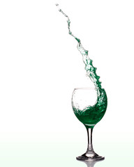 grüne Flüssigkeit spritzt aus einem Weinglas