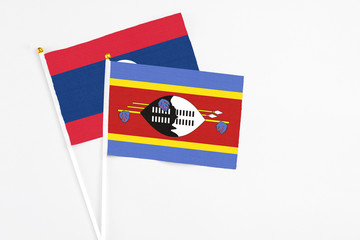 Swaziland and Laos stick flags on white background. High quality fabric, miniature national flag. Peaceful global concept.White floor for copy space.