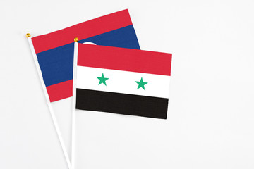 Syria and Laos stick flags on white background. High quality fabric, miniature national flag. Peaceful global concept.White floor for copy space.