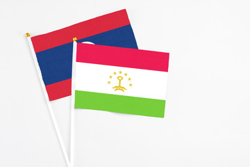 Tajikistan and Laos stick flags on white background. High quality fabric, miniature national flag. Peaceful global concept.White floor for copy space.