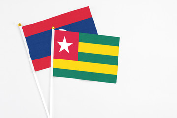 Togo and Laos stick flags on white background. High quality fabric, miniature national flag. Peaceful global concept.White floor for copy space.