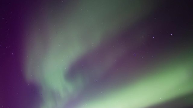 Green and Purple aurora borealis on starry sky background.