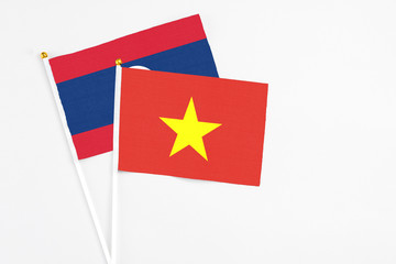 Vietnam and Laos stick flags on white background. High quality fabric, miniature national flag. Peaceful global concept.White floor for copy space.