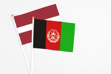 Afghanistan and Latvia stick flags on white background. High quality fabric, miniature national flag. Peaceful global concept.White floor for copy space.