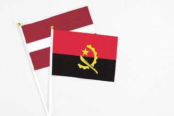 Angola and Latvia stick flags on white background. High quality fabric, miniature national flag. Peaceful global concept.White floor for copy space.