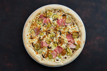 Top view of pizza with bacon, mushroom, pickled cucumber and caramelized onion