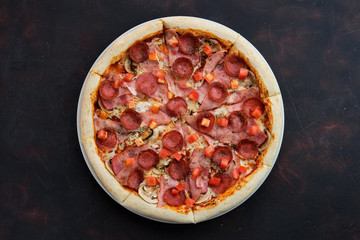 Top view of pizza with ham, bacon, sausage, tomato and champignon