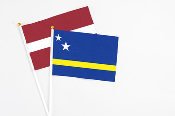 Curacao and Latvia stick flags on white background. High quality fabric, miniature national flag. Peaceful global concept.White floor for copy space.
