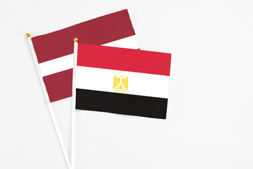 Egypt and Latvia stick flags on white background. High quality fabric, miniature national flag. Peaceful global concept.White floor for copy space.