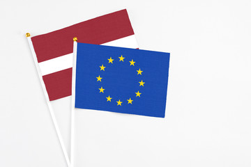 European Union and Latvia stick flags on white background. High quality fabric, miniature national flag. Peaceful global concept.White floor for copy space.