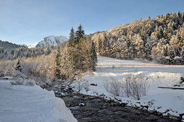 Fototapeta na wymiar Beautiful peaceful winter landscape in the Frence Alps, at one of the ski stations, France. Mountain river at the forefront