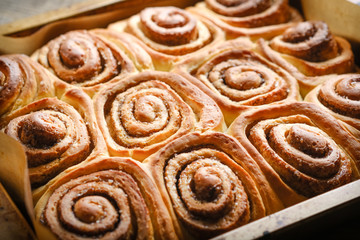 Fresh homemade cinnabons baked in metal form on a light rustic background top view. Homemade baking.