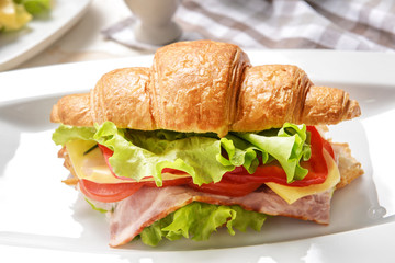 Tasty croissant sandwich on plate, closeup