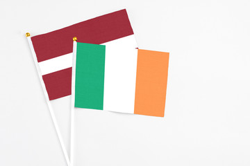 Ireland and Latvia stick flags on white background. High quality fabric, miniature national flag. Peaceful global concept.White floor for copy space.