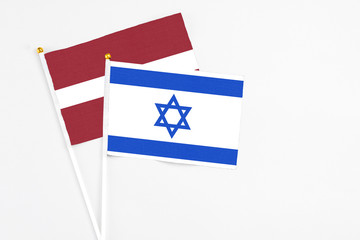 Israel and Latvia stick flags on white background. High quality fabric, miniature national flag. Peaceful global concept.White floor for copy space.