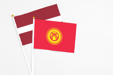 Kyrgyzstan and Latvia stick flags on white background. High quality fabric, miniature national flag. Peaceful global concept.White floor for copy space.