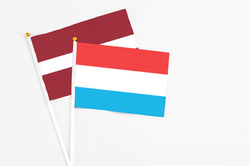 Luxembourg and Latvia stick flags on white background. High quality fabric, miniature national flag. Peaceful global concept.White floor for copy space.