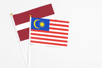 Malaysia and Latvia stick flags on white background. High quality fabric, miniature national flag. Peaceful global concept.White floor for copy space.
