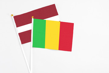 Mali and Latvia stick flags on white background. High quality fabric, miniature national flag. Peaceful global concept.White floor for copy space.
